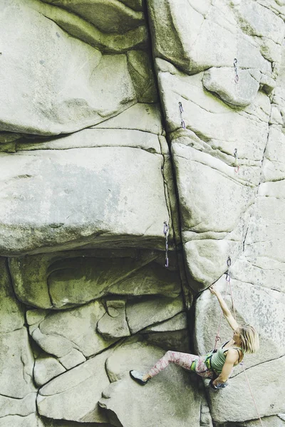 Dívka leze na skálu na horolezecké trasy. — Stock fotografie
