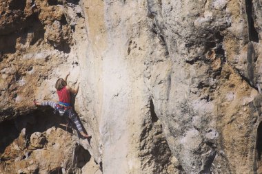Kadın dağcı. Kaya tırmanışçısı kayalık bir duvara tırmanıyor. Kadın m