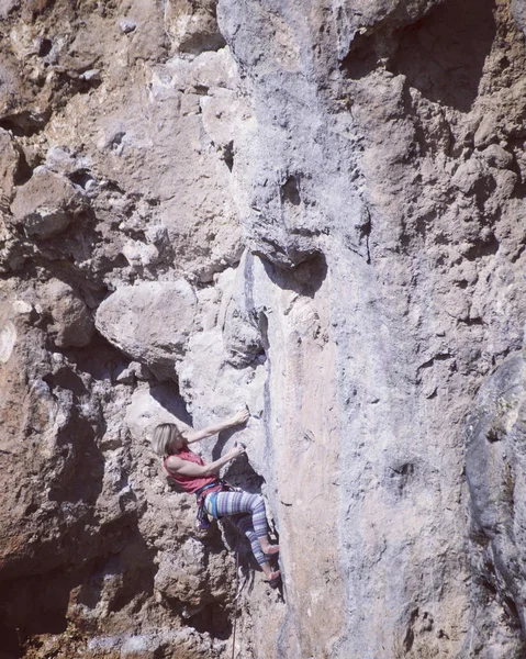 Mujer escaladora de rocas. Escalador de rocas sube a una pared rocosa. Mujer m —  Fotos de Stock