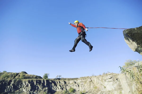 Jump off a cliff into a canyon with a rope. Stock Picture
