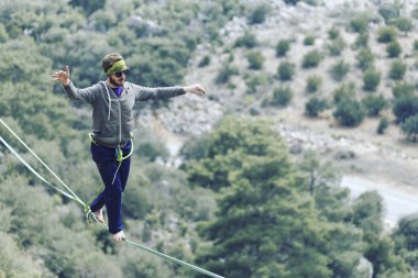 Bir adam gergin bir sapan boyunca yürüyor. Mounta Highline