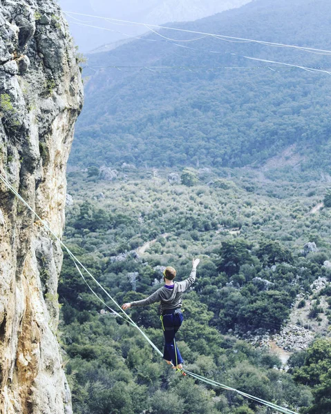 Un hombre camina a lo largo de una honda estirada. Highline en la montaña — Foto de Stock