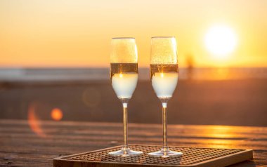 Gün batımında masada iki kadeh şampanya.