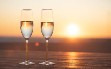 Gün batımında masada iki kadeh şampanya.