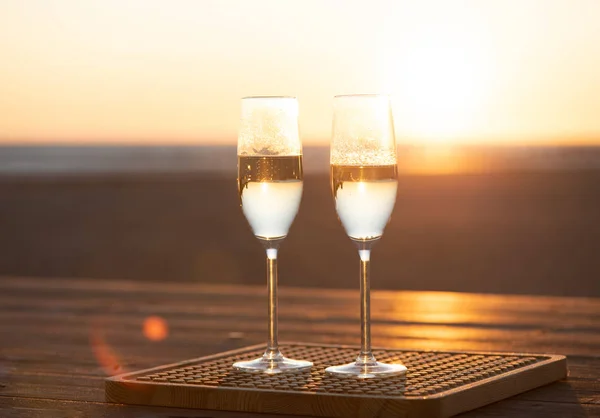 Gün batımında masada iki kadeh şampanya.