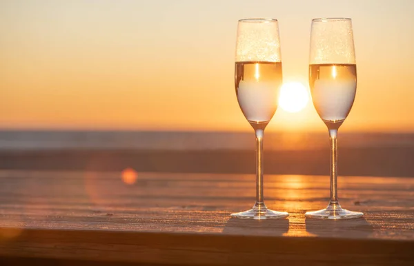 Gün batımında masada iki kadeh şampanya.