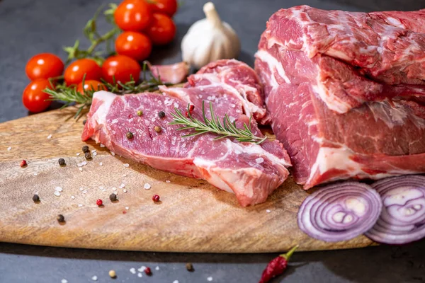 Koyu çimento arka planında kesilmiş çiğ et ve sebzeler