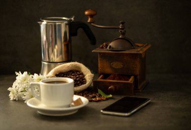 Kahve çekirdekli beyaz kahve fincanı ve beyaz çiçekli kahve öğütücüsü.