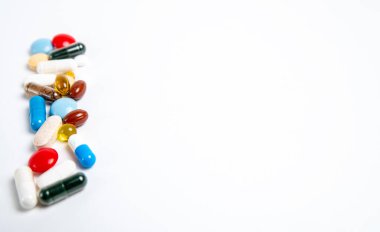 Beyaz arka planda, sol tarafta bir sürü renkli hap var.