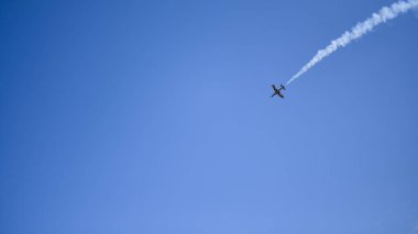 Uçak mavi gökyüzüne karşı sağ üst köşeden uçuyor.