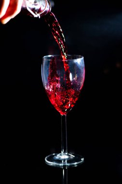 Bekar. Kırmızı şarap döker ve siyah bir arka plana dökülür.