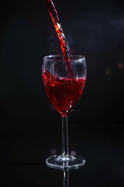 Bekar. Kırmızı şarap döker ve siyah bir arka plana dökülür.