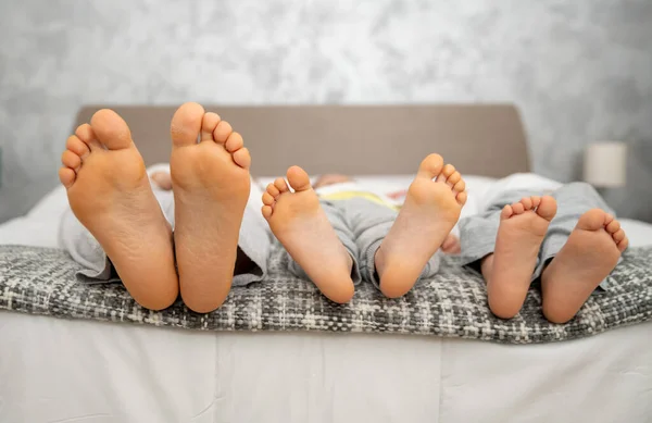 Evde kal, yatakta üç çift bacak anne ve çocuklar.