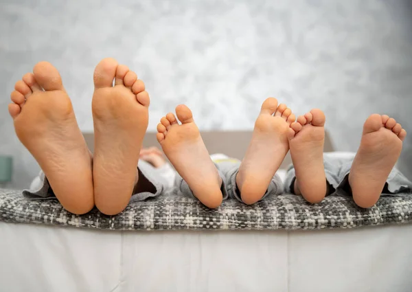 Evde kal, yatakta üç çift bacak anne ve çocuklar.