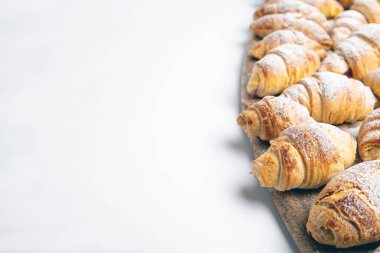 homemade fresh baked croissant with cinnamon, jam and coffee on a white table.
