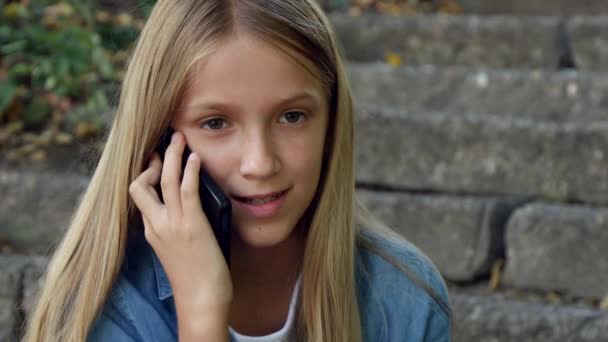 스마트 폰에 이야기 하는 아이, 스마트폰을 사용 하 여 아이, 공원에서 야외 에서 노는 여자 — 비디오