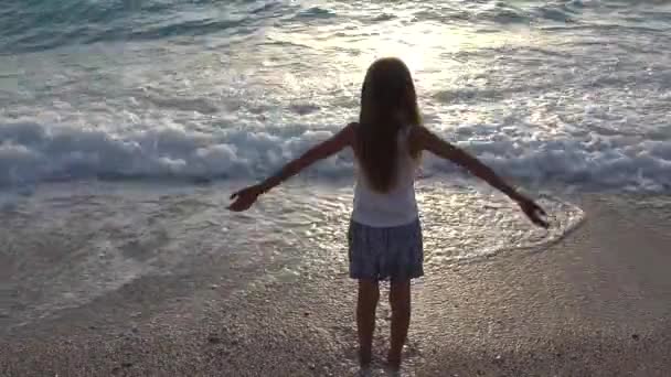 Criança brincando na praia ao pôr do sol, Criança assistindo ondas do mar, Menina feliz na costa — Vídeo de Stock