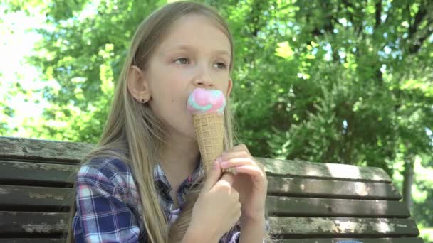 Kid jíst zmrzlinu v parku, dítě relaxační sezení na lavičce dívka na hřišti — Stock video