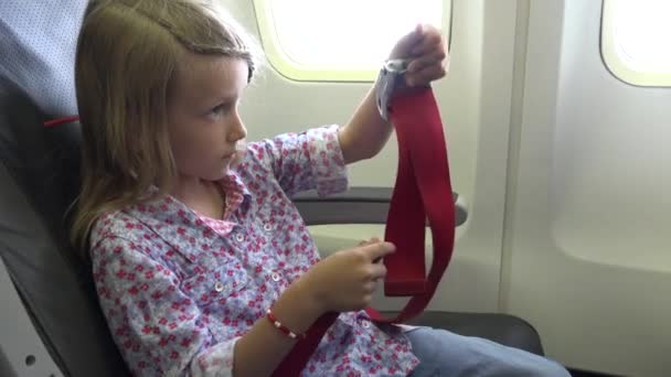 4Kキッド飛行機での旅行,子供は安全ベルトを置く,飛行機の女の子,シートベルト — ストック動画