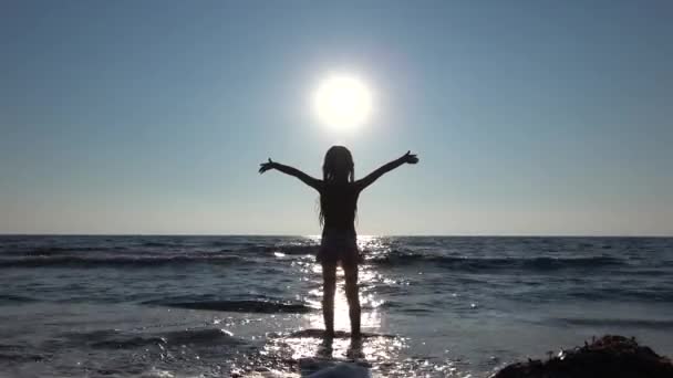 4K Kid che gioca sulla spiaggia nei raggi del sole, Silhouette Girl in Sunbeam Coastline, Vista estiva sul mare — Video Stock