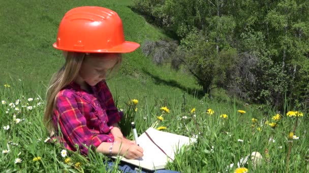 4K-Kid-Ingenieur im Helm schreibt auf Notizbuch, Kind auf Wiese, Mädchen spielen im Freien in den Bergen lächelnd — Stockvideo