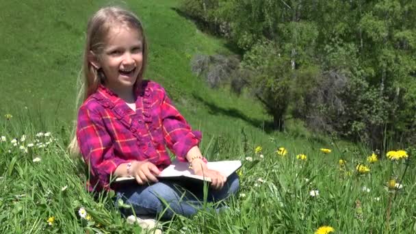 4K Layghing Kid, czytanie dzieci w parku, dziewczyna grająca książkę na świeżym powietrzu na łące w górach — Wideo stockowe