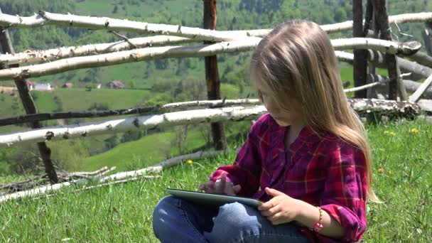 4K Kid hraje na tabletu, Dítě hraje na louce, Dívka pomocí pracovního smartphonu na výlet v horách — Stock video