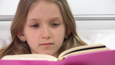 Çocuk yatakta kitap okuyor, çocuk çalışıyor, kız uyuduktan sonra yatak odasında öğreniyor.