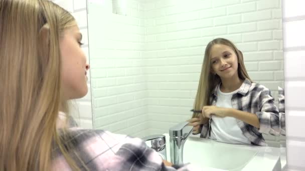 Ребенок расчесывает волосы в зеркале, ребенок причесывается в ванной, блондинка расчесывается — стоковое видео