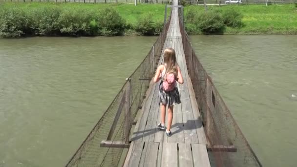 Niña en el puente en las montañas, Senderismo infantil en la naturaleza, Niña mirando un río, Corriente — Vídeo de stock