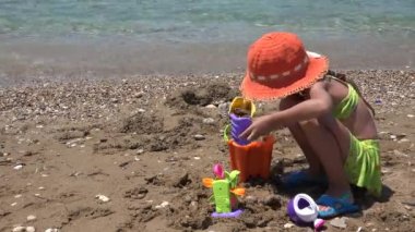 Gün batımında Sahilde Çocuk Kalesi Yapıyor, Deniz kenarında Çocuk Kumları Oynuyor, Kız Denizden Oynuyor