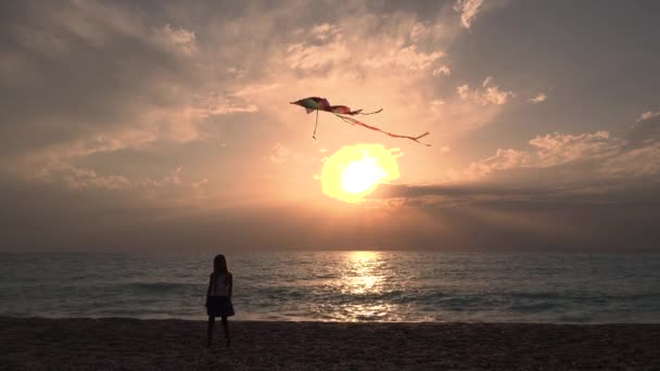 Niño jugando en la playa en la orilla del mar, Niño volando cometa al atardecer en el océano, Niña feliz en la costa — Vídeo de stock