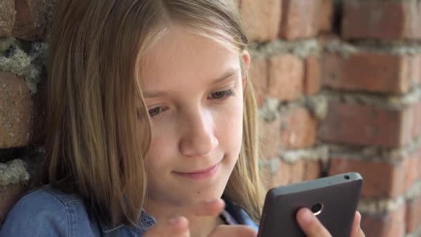 Niño usando Smartphone, Niño jugando a chatear en el teléfono inteligente, Adolescente chica al aire libre navegar por Internet en el parque — Vídeos de Stock