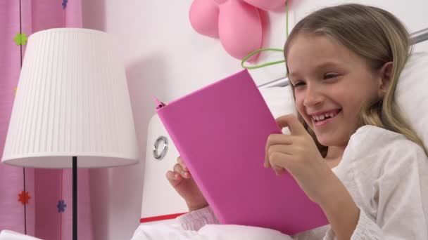 Dziecko czyta książkę w łóżku, dziecko śmieje się studiuje, dziewczyna uczy się w sypialni po spaniu — Wideo stockowe