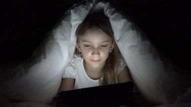 Çocuk karanlık gecede tablet oynuyor, kız yatakta internete bakıyor, çocuk uyumuyor.