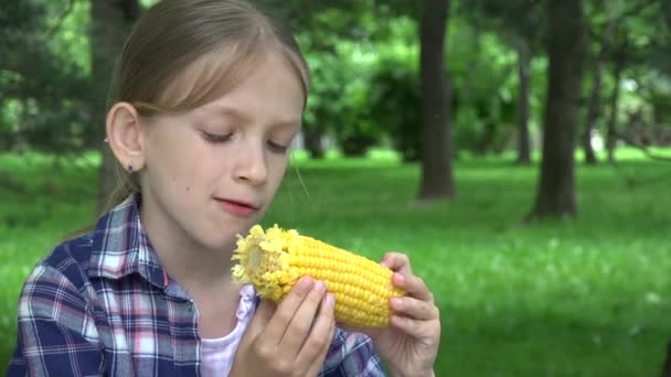Criança comendo milho cozido ao ar livre no parque, garota faminta come comida saudável, criança relaxante ao ar livre na natureza — Vídeo de Stock