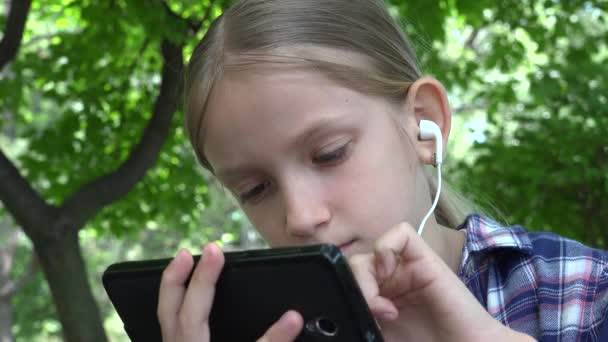 Kind spielt Tablet auf Spielplatz im Park, Mädchen surfen im Internet, Kind nutzt Smartphone — Stockvideo