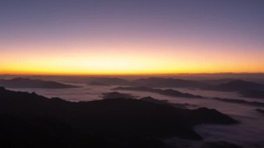 Güzel manzaralı Timelapse gündoğumu bulutları hareket ettirerek ya da sisli turuncu gökyüzü ve cennet tepesinin zirvesinde güneş ışığı..
