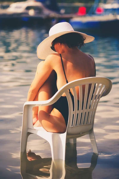 물에의 자에 앉아 sunhat 여자 — 스톡 사진