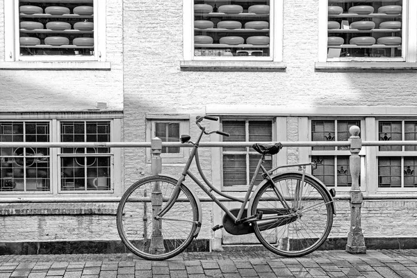 Oude fiets en kaas in de showcase van de winkel in de stad Delft, Nederland — Stockfoto