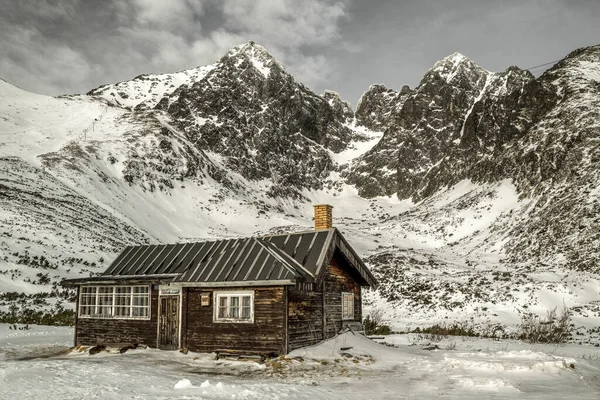 Ξύλινο εξοχικό σπίτι και χιονισμένα βουνά — Φωτογραφία Αρχείου
