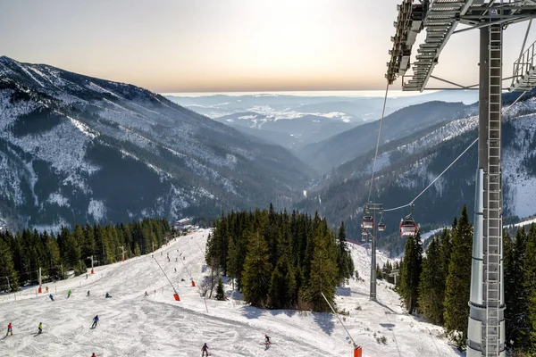 Uitzicht vanaf kabelbaan op piste en skiërs in resort Chopok Juh, Slo — Stockfoto