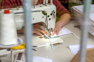 Dikiş makinesine yüz maskesi dikiyorum.