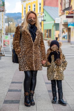 RUZOMBEROK, SLOVAKIA - 31 Mart 2020: Yüzü maskeli bir anne aynı kıyafetleri giyiyor ve moda hayvan leoparı modasında