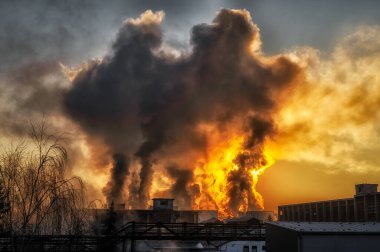 Fabrikada ve gün doğumunda bacalardan siyah duman çıkıyor. Ruzomberok, Slovakya 'daki fabrika