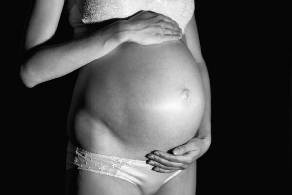 Pregnant caucasian woman 9 month holding her belly. Black and white photo