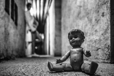 Hamile kız karanlık tünelde yaşlı korkunç bir bebekle poz veriyor.