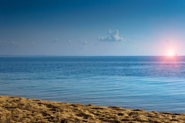 Sabahın erken saatlerinde deniz manzarası. Güneş ufukta belirdi. Sakin deniz. Deniz kıyısından kabuk kayasına.