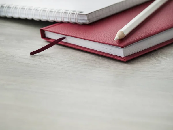 Akcesoria biurowe: czerwony Notatnik, biały Notatnik i ołówki na drewnianym szarym biurku. Wróć do szkoły. ? przegrywają. Widok z góry. Kopiuj przestrzeń — Zdjęcie stockowe