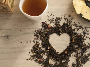 Çay kavramı. Çiçek kuru çay bir ahşap masa, beyaz fincan çay üzerinde kalp şeklinde. Plaka peynir ile. Sevgililer günü. Aşıklar. Üstten Görünüm. Kopya alanı